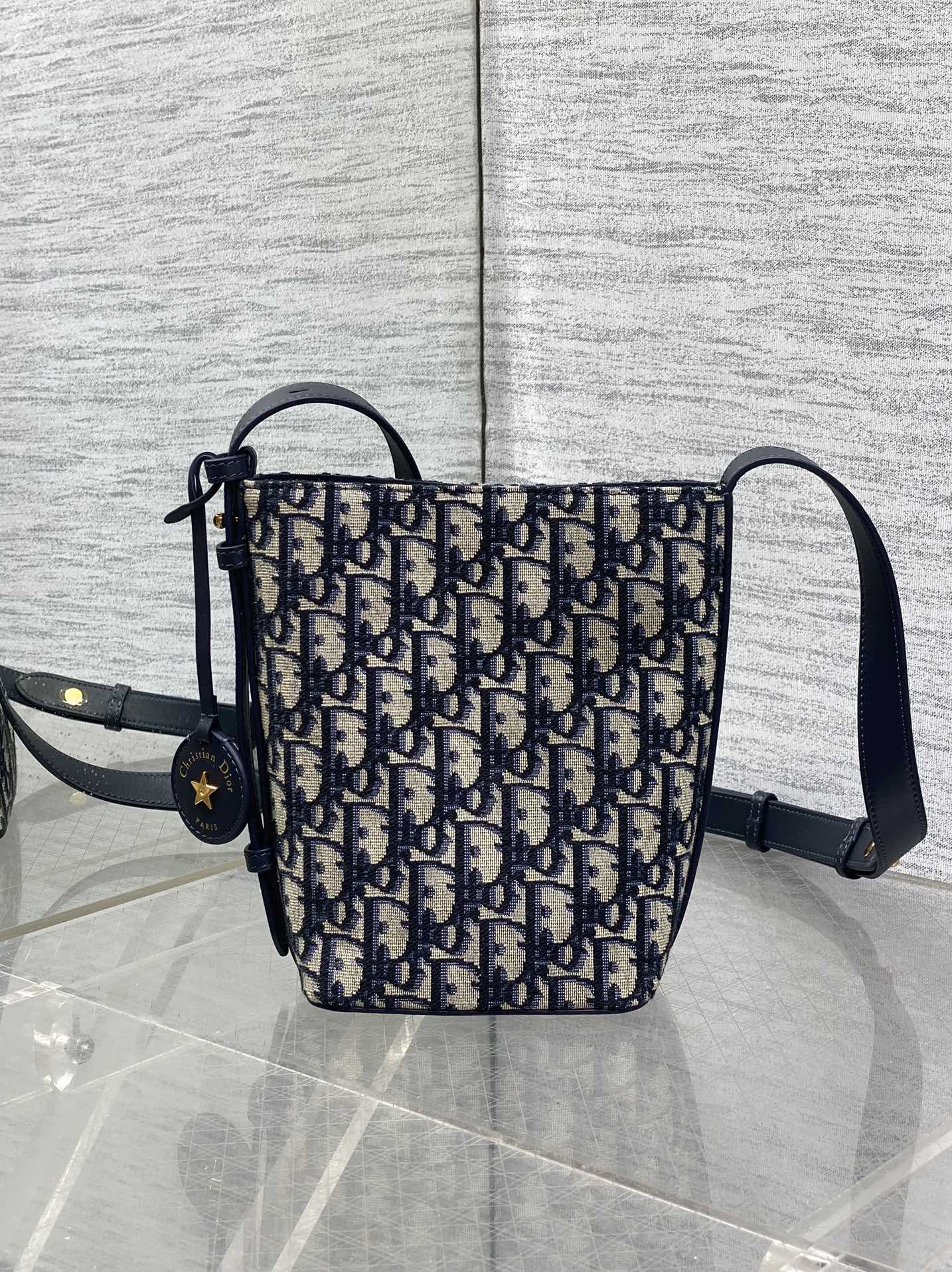 In Stock‼️ Dior's New Star Bucket Bag Collection The latest stunning handbags have arrived! Crafted from classic Oblique monogram fabric with exquisite workmanship, this adorable bucket bag design blends elegance with modern style. Its soft silhouette features a drawstring closure and removable long shoulder strap, combining practicality with beauty. Perfect for holiday outings—carry it with flair wherever you go!