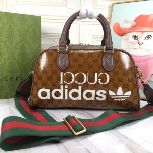 Batch 390...🔥🔥 adidas x Gucci Collaboration Mini Travel Bag. As part of the adidas x Gucci collaboration collection, this mini travel bag features "Gucci adidas" and Trefoil prints. adidas and Gucci boldly explore this collaborative series, where woven straps and GG lettering patterns artfully complement the white three stripes and Trefoil logo.Drawing inspiration from the creative director's nostalgic memories of the 80s and 90s, the collection merges both brands' rich heritage and iconic design language to shape distinctive styles. "Gucci adidas" and Trefoil print white leather trim adidas x Gucci collaboration series, red and green woven straps, interlocking double G and Trefoil print cotton-linen lining. Model: 702397.Dimensions: 31.5*18*15.5cm. Color: White leather/adidas collaboration edition.