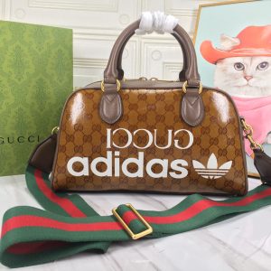 Alternative view of Batch 390...🔥🔥 adidas x Gucci Collaboration Mini Travel Bag. As part of the adidas x Gucci collaboration collection, this mini travel bag features "Gucci adidas" and Trefoil prints. adidas and Gucci boldly explore this collaborative series, where woven straps and GG lettering patterns artfully complement the white three stripes and Trefoil logo.Drawing inspiration from the creative director's nostalgic memories of the 80s and 90s, the collection merges both brands' rich heritage and iconic design language to shape distinctive styles. "Gucci adidas" and Trefoil print white leather trim adidas x Gucci collaboration series, red and green woven straps, interlocking double G and Trefoil print cotton-linen lining. Model: 702397.Dimensions: 31.5*18*15.5cm. Color: White leather/adidas collaboration edition.