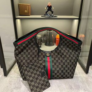 Lot 320...GG Giglio Large Tote, newly unveiled at the Florence 2026 Pre-Spring Fashion Show, pays homage to the brand's Italian heritage, blending timeless tradition with innovative spirit. This spacious tote is expertly crafted from GG canvas, adorned with woven ribbon piping, and includes a detachable clutch.Product Details · Off-white and dark brown GG canvas · Red and green woven ribbon piping · Green cotton lining · Double G logo · Includes detachable clutch · Magnetic snap closure Model: 853971 Dimensions: 60x47x16cm