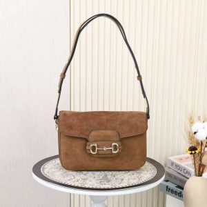 Batch 340... Fall/Winter 2025 Collection. This shoulder bag reinterprets the brand's equestrian-inspired design, featuring light gold-tone details and suede material, complemented by double rings and elongated hardware, adding to the Gucci Horsebit 1955 series.Brown suede with gold-tone hardware. Brown leather lining. Horsebit clasp. Interior: One open pocket. Three-compartment design. Adjustable shoulder strap. Height: 28 cm – 50 cm; Length: 71 cm – 114 cm. Model: 847063.Dimensions: 26 cm (width) x 17.5 cm (height) x 10 cm (depth) Weight: Approx. 0.85 kg Color: Brown suede/natural leather.