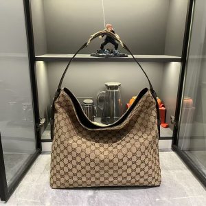 Batch 350... Fall/Winter 2025 Collection. The G G Beatrix handbag is meticulously crafted from cowhide leather, featuring a shoulder strap adorned with the iconic horsebit detail that infuses the relaxed silhouette with brand identity.Gold-tone hardware elevates its refined aesthetic, while an interior zippered pocket securely holds essentials. Blending elegant design with practicality, it effortlessly accommodates daily necessities. Brown GG suede, gold-tone hardware, cotton-linen blend lining. Shoulder strap with horsebit detail. Model: 850546. Dimensions: 40 x 36 x 12 cm.