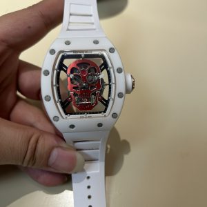 YS Richard Skull Ceramic Case True Tourbillon Skull Series  Richard Mille RM52-01  True Tourbillon, reinterpreting the essence of RICHARD MILLE's skull motif, overcoming bugs across multiple versions to deliver an ultra-high-quality replica with accurate dimensions, authentic movement, and meticulous detailing for dedicated collectors.Reasons to Own: 1. Near-identical dimensions: Official: 50*43*16mm; YS Factory: 49.8*44.3*16.4mm;2. Authentic Bearings: The ruby in the skull's mouth serves as the tourbillon's genuine bearing, not mere decoration. The gem aligns with the tourbillon's central axis encased by the upper and lower jaws, evoking the image of swallowing an energy sphere and capturing the sci-fi aesthetic intended by the original design.3. Meticulous Details: The inner left wall of the case cover bears the RM052 stamp identical to the original. The right eye gear matches the original in size and depth. The central gemstone on the forehead is vividly red and translucent. Features include a brushed buckle and a rubber strap made from imported Thai material.4. Movement Alignment: Thanks to the tourbillon's identical position and size to the original, the movement's operation is clearly visible from the back beneath the skull's occipital region. From the front, the black balance wheel is precisely obscured by the skull's lower jaw, leaving only the escape wheel visible beneath the skull.5. Inner and Outer Excellence: The movement is a custom-made genuine tourbillon caliber from Shanghai Watch Movement Factory. Each watch undergoes rigorous QE timing tests on a high-intensity simulator and features enhanced water resistance. JB Factory—Crafted with Heart and Soul! This is another masterpiece following the Double Tourbillon, RM001, Roger Dubuis Royal, RM053, Rolex Tourbillon, and Classic Fusion!Each YSFactory tourbillon comes with a complimentary genuine leather protective pouch.