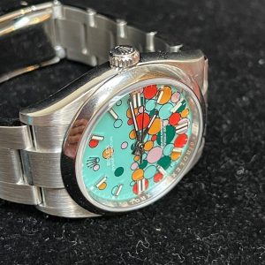 Alternative view of The 2023 new Oyster Perpetual series 126000 and 124300 Balloon Edition, the pinnacle 36.41mm models, have arrived. The quality of this release is truly exceptional. Jointly crafted with N+AR original factory, the dedicated manufacturer has implemented a series of improvements alongside this upgrade! The value for money is also outstanding! It features the ETA2836 automatic mechanical movement with a daily deviation as low as 0.3 seconds!Why choose this movement? First, it's widely recognized for its reliability—outperforming common alternatives like the 2824 and the monobloc 3230 in stability!Second, the Oyster Perpetual's crown position is centered, with the crown tube seamlessly integrated into the case to achieve perfect crown alignment. Among all movements, the 2836 is uniquely suited for this crown alignment! The ultra-vibrant ice-blue luminescence and the AR factory's brushed bracelet are absolute standout features among all Oyster models from this manufacturer!It is absolutely not a modified Rolex Oyster case found elsewhere on the market. It features a unique Oyster case design. Measured at 41.36mm including the crown position, it perfectly matches the 41mm replica size—an exclusive custom replica dimension from this manufacturer! Rolex's 2023 new Oyster collection has garnered immense popularity since its launch. The dial features 51 replica balloons!The stunning 3D effect is utterly captivating! Both 36mm and 41mm sizes are available, with limited stock arriving now! Order quickly! [Rose]